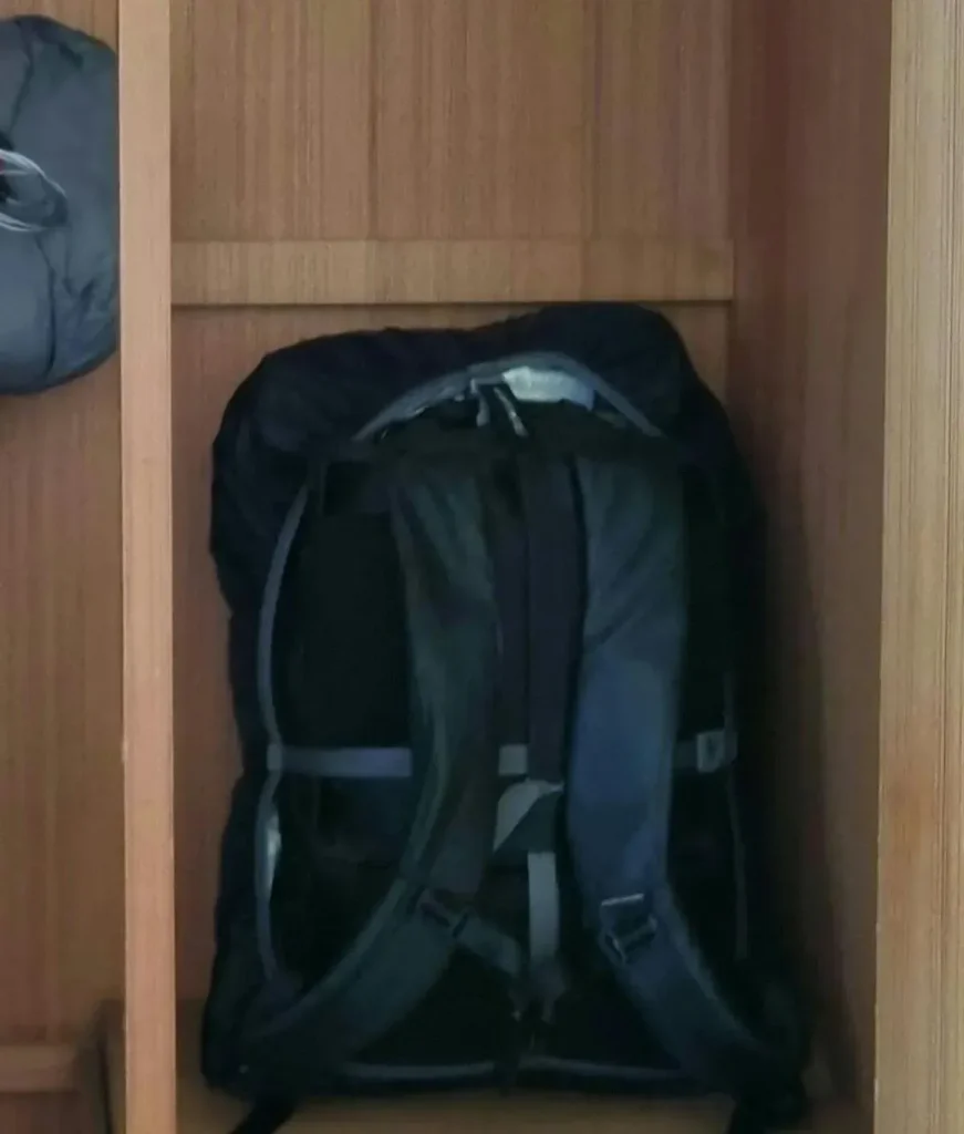 Carryon-sized 30 liter backpack (a.k.a in-cabin baggage) resting within a hotel clothing & storage dresser. It has a rain cover over it that has an elastic band around it's permiter - good for stuffing things inside (between the bag and the rain cover), preventing theft. The rain cover, per the name, protects against water as it is made of water-resistant material.