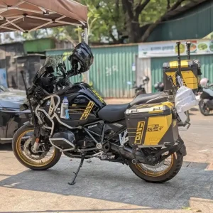 A BMW 1250 cc motorcycle in Southeast Asia, which is very large for Southeast Asia. The motorcycle has accessories on it such as saddle bags for storage, a cup holder, and an antenna. The "cc" stands for "cubic centimeters", referring to the engine size.