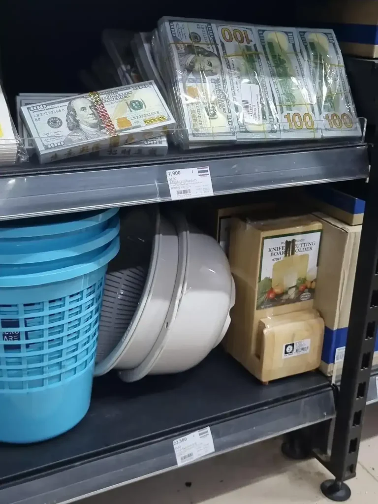 Stacks of buddhist money in the form of fake 100 US dollar bills for sale at a grocery store. The intention is to give this money to those in the after life, where it would be deemed legal tender.