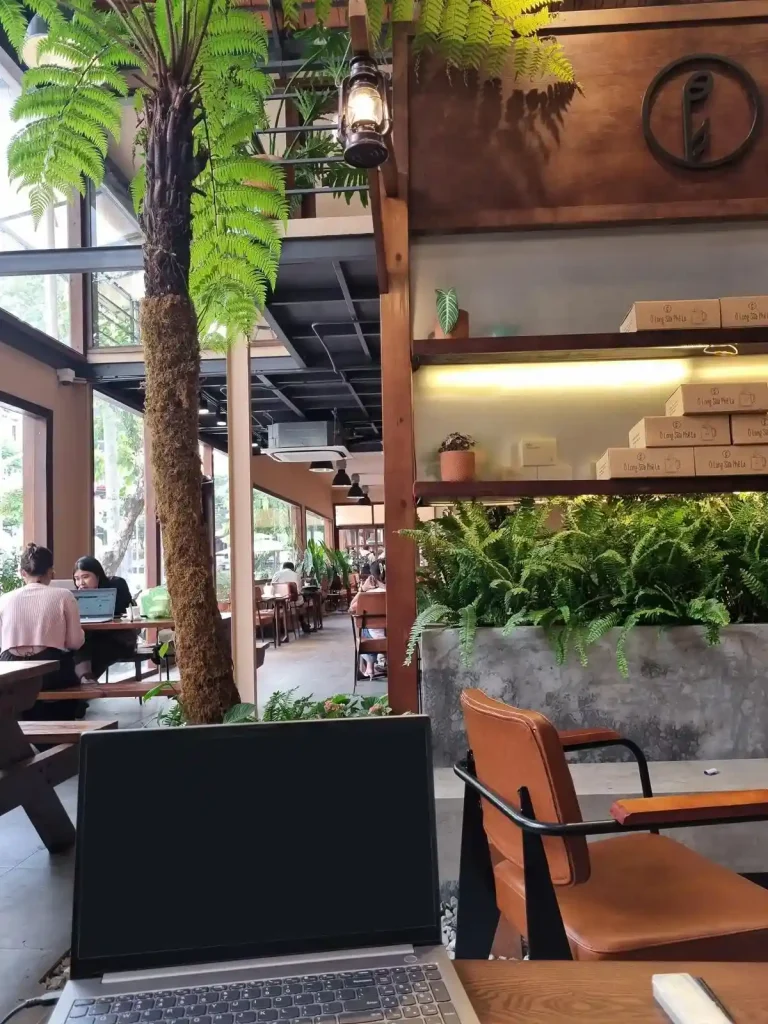 A café with a laptop on a desk and seating. This represents a place to work from for remote workers in Southeast Asia.