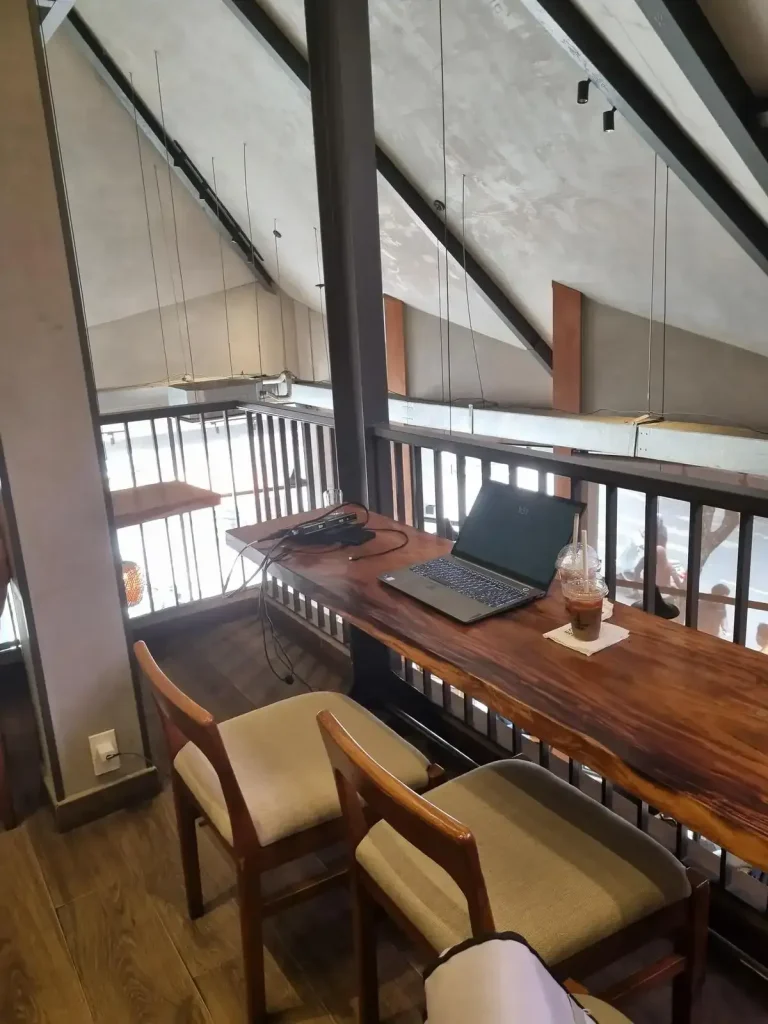A café with a laptop on a desk and seating. This represents a place to work from for remote workers in Southeast Asia.