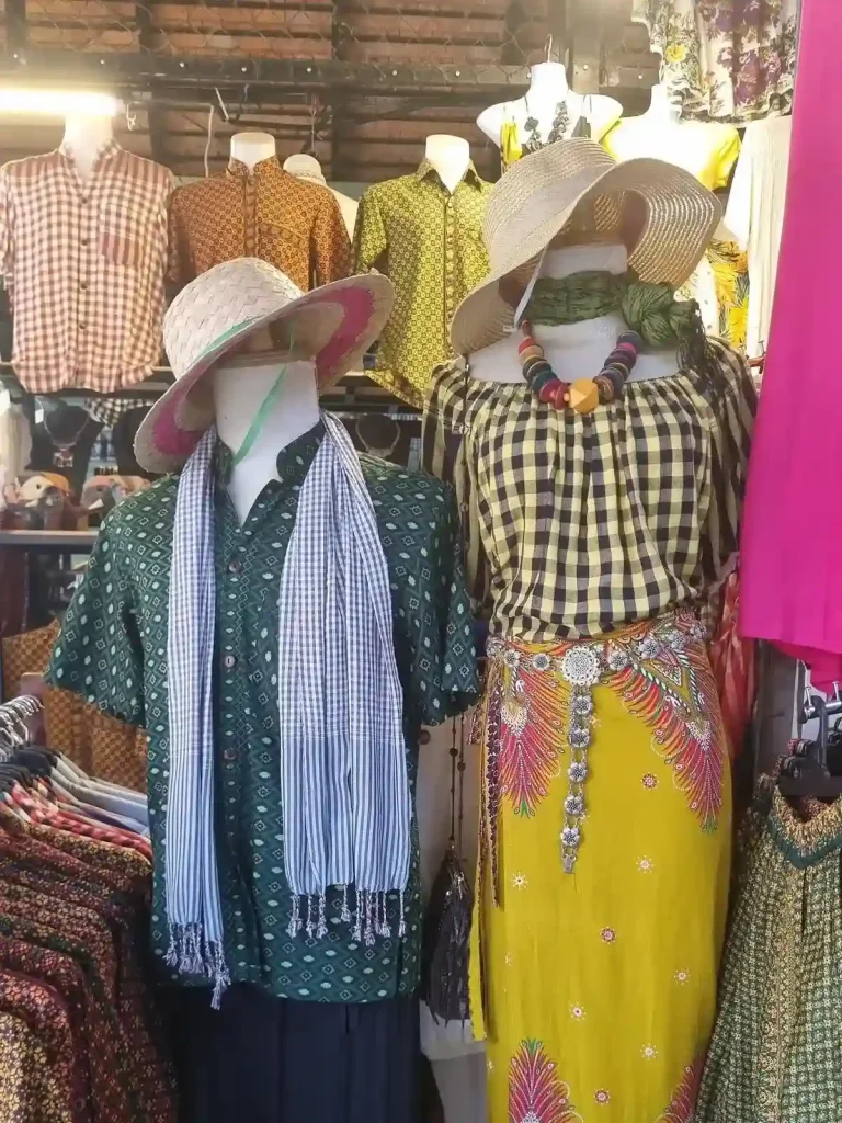 A store selling to tourists. A typical Cambodian-style short-sleeve men's shirt, women's shirt and pants. Both mannequins are wearing Cambodian-style straw hats.