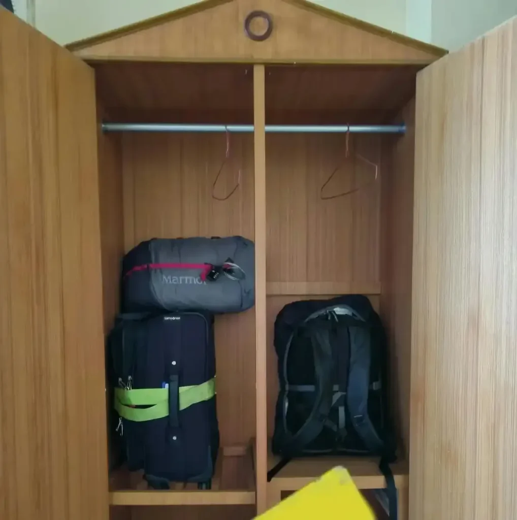 2 carry-on travel bags - one small and one medium sized - and a check-in luggage bag inside a hotel clothing and storage dresser. This picture conveys the different sizes of the bags.