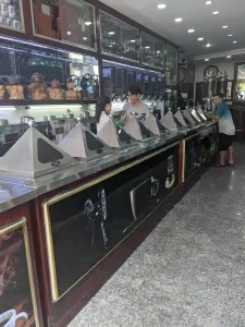 A shop specializing in selling coffee beans with 10 different varieties shown in this image. The beans are all integrated within a long counter, with staff located behind the counter to assist you.