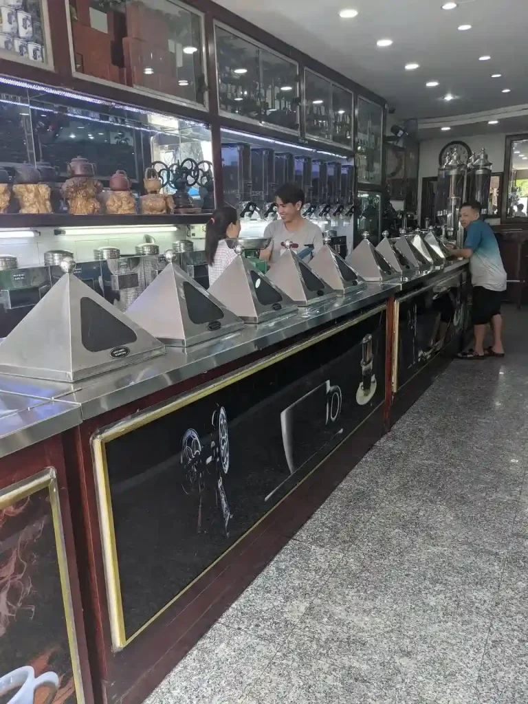 A shop specializing in selling coffee beans with 10 different varieties shown in this image. The beans are all integrated within a long counter, with staff located behind the counter to assist you.