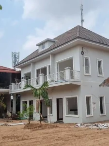 An image showing the construction method in Southeast Asia for building homes. This two story apartment building is still under construction. A concrete skeleton was constructed on a foundation. Then, brick was laid to fill in the skeleton, building the outer and inner walls of the home. Finally, concrete is smeared over the brick and smoothed out for a smooth texture. Roofing is made of clay.