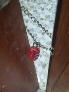 An image showing how a door cannot be fully opened. A chain and travel lock are used to lock the door from the outside as an extra means to prevent people coming into an apartment, home, or studio room. Unwanted people include landlords who have a spare key, or anyone who can get access to a spare key.