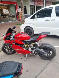 A sport motorcycle (aka crotch rocket) made by Ducati. The motorcycle is parked at a gas station. Location: Cambodia.