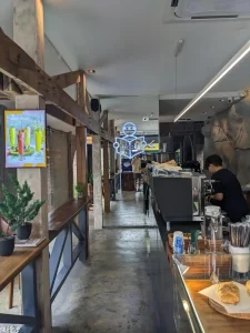 The coffee bar section inside of fancy café in Southeast Asia. An expresso machine is present, and a croissant on the counter.