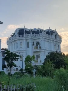 A very fancy four story mansion house in Vietnam. The fourth story appears to be a roof, but there are windows, so it is livable. This house has elaborate decorations.