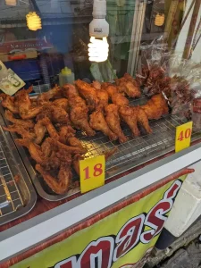 Fried chicken being sold in Thailand. Wings are eighteen Thai Baht (about sixty US cents), and chicken legs are forty baht (about one US dollar and twenty-five cents).