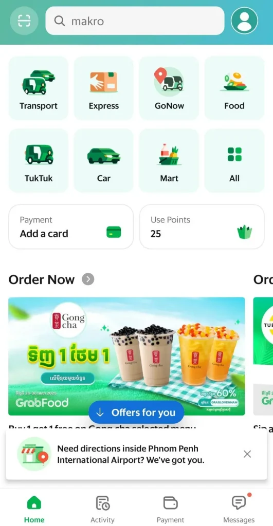 A screenshot of the Grab ride hailing smart phone application. This is the "front page" of the app, so to speak. Selectable categories are: "Transport" for ride hailing, "Express" for mailing, "GoNow", "Food" for ordering and having food delivered, "All" for more categories, "Mart" for ordering things from a convenience store or grocery store, "Car" and "TukTuk" for ride hailing. There is a "Payment: Add a card option", which is optional - you can pay with cash, instead. There is also a "Use Points" box that displays accumulated points that an app user has. At the bottom of the app are "Home", "Activity", "Payment", and "Messages". Note that this app has a messaging system with built-in translation. You type English - they see their native language, and vise-versa when they message you.