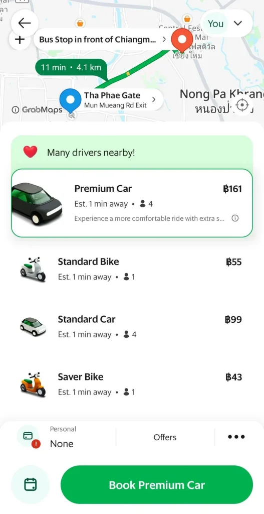 A screenshot of the Grab smart phone app for ride hailing in Thailand. This shows the available options to book a car or motorbike (scooter). Premium Car: one hundred and sixty-one Thai Baht (roughly five US dollars), standard bike (motorbike): fifty-five Thai Baht (roughly two US dollars), Standard Car: ninety-nine Thai Baht (roughly three US dollars), and Saver Bike: forty-three Thai Baht (roughly one and a half US dollars).
