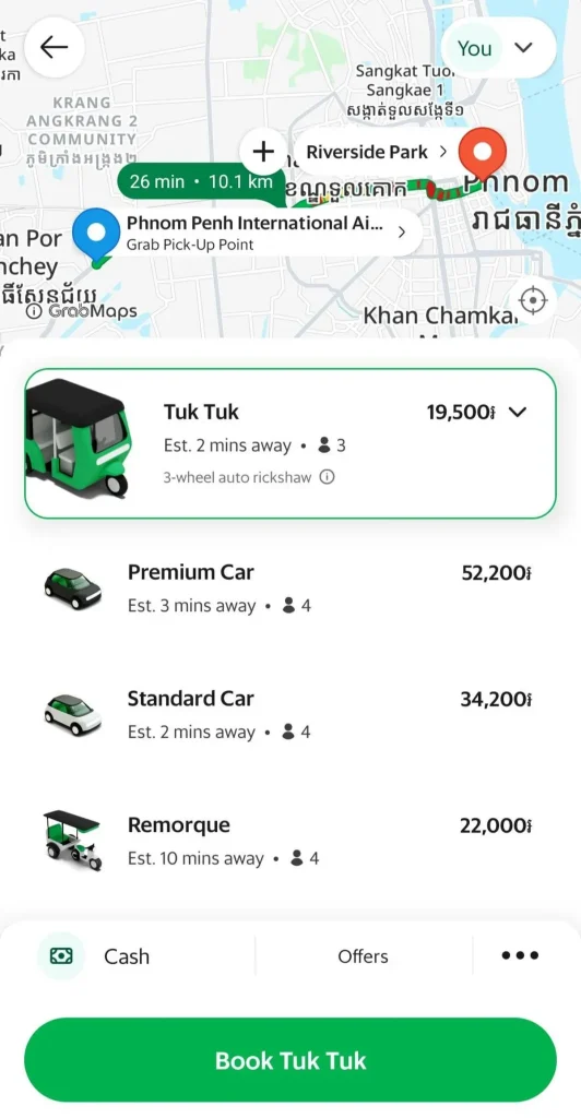 A screenshot of the Grab smart phone app for ride hailing in Cambodia. This shows the available options to book a tuk-tuk, car or remorque (wagon tuk tuk). Tuk Tuk: nineteen-thousand five hundred Cambodian Riel (roughly five US dollars), Premium Car: fifty-two thousand and two hundred Cambodian Riel (roughly thirteen US dollars), Standard Car: thirty-four thousand and two hundred Cambodian Riel (roughly eight and a half US dollars), and Remorque: twenty-two thousand Cambodian Riel (roughly five and a half US dollars),