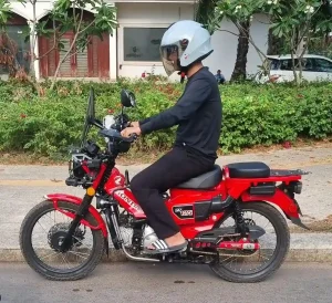 A Honda CT 125 semi-automatic motorbike (scooter) with a rider on it in Cambodia.