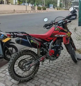 A Honda dirtbike in Laos with turn signals and rear-view mirrors. This dirtbike is parked on a sidewalk.