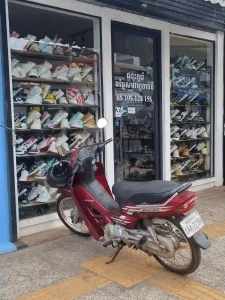 A Honda Dream 125cc semi-automatic motorbike (scooter) parked on a sidewalk in front of a store in Cambodia.