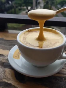 An image of a hot egg coffee in a café in Vietnam called Little Hanoi Cafe. Egg coffee is similar to a late, but with cream that includes egg in it's ingredients, instead of steamed milk. It does not taste like egg.