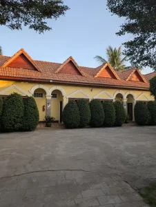 A hotel in Southeast Asia. It is a slightly fancier version of an American motel with a corridor walkway to each room and large bushes in front.