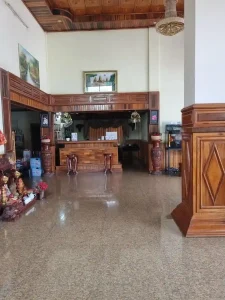 The interior lobby of a hotel in Cambodia. It is filled with wooden paneling and decoration.