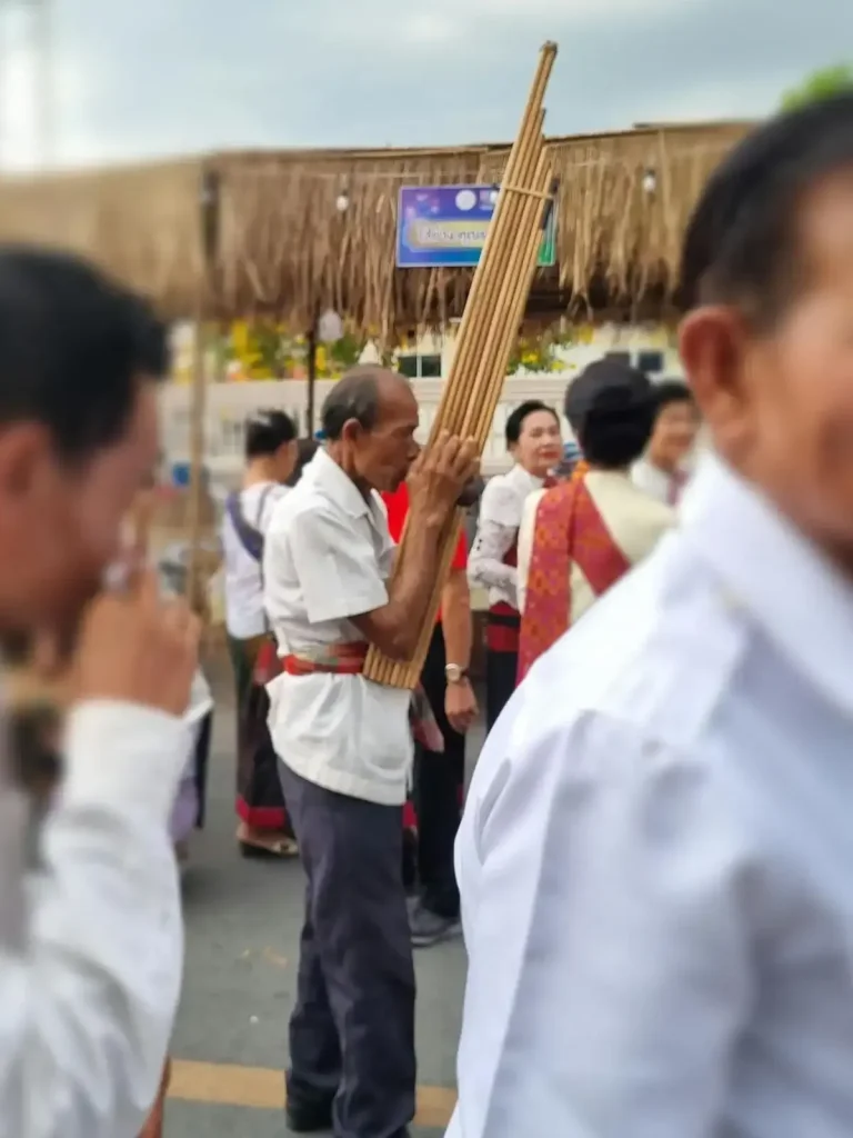 A local man playing a Laos Khaen (also written as Khene) instrument during a parade and festival festivities in Korat Thailand. This instrument is similar to a small organ and a flute combined. It has eight bamboo flutes connected together, with one single hole that the player blows into. Each "flute" has one hole that the player can cover with their finger tips to play a note. This instrument is also found in Isaan Thailand, as this region has a historical tie to Laos.