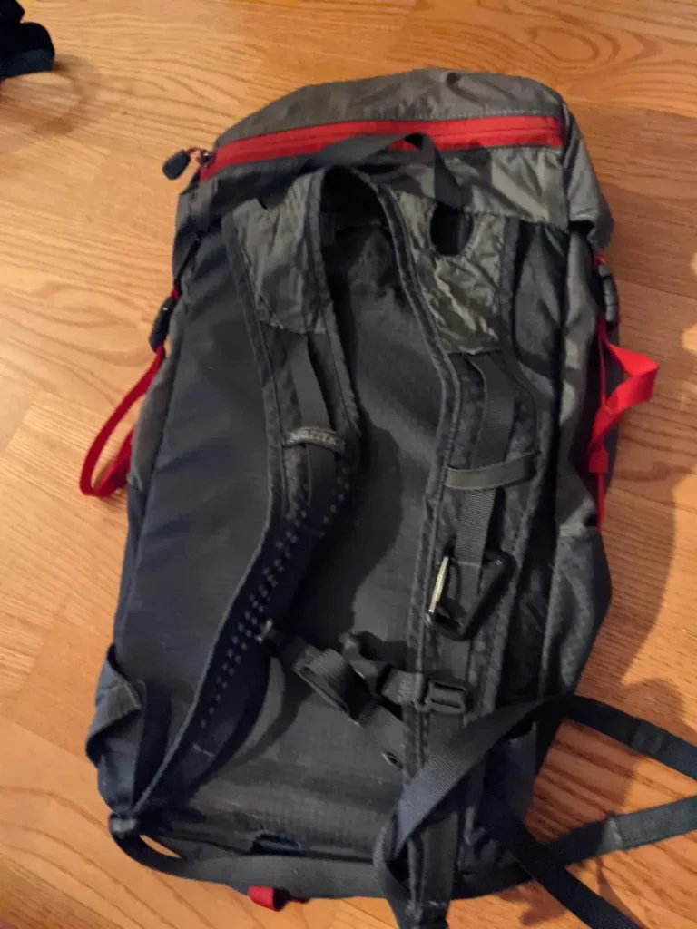 Back size view (the side with the back/shoulder straps) of an empty 18 liter day bag. This bag is lightweight, and made by Marmot brand.