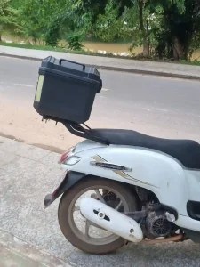 A motorbike (scooter) in Southeast Asia with storage box mounted on the rear rack.