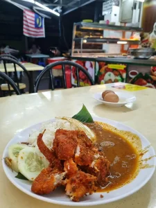 A dish in Malaysia called Nasi Lemak Ayam Goreng. Nasi (rice) Lemak (which is just a name?) Ayam (chicken) Goreng (fried) is fried chicken on rice cooked with coconut milk, sambal as a sauce, a fried egg, sliced cucumber, fried anchovies, and peanuts. This is dish is on display on a table at an open-air Indian-Malaysian restaurant called a Mamak or Nasi Kandar.
