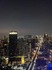 A rooftop view of Bangkok city, Thailand at night with high rise buildings everywhere. Lights light-up the buildings and roads.