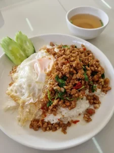 A dish in Thailand called "Pad Krapao Kai Dao". This is stir fried diced pork with Thai basil and red chillies added to liking, with a fried egg, and sliced cucumber on the side. A simple bowl of soup is included, with broth and some scalions thrown in.