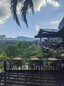 Café seating and layout with mountains in the background at a café in southern Thailand. A palm oil plantation with a forrest of palm trees covers the land between the café and mountains.
