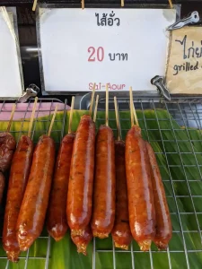 A street food stall in northern Thailand selling long and thin grilled sausage at a price of twenty Thai Baht (about 65 US cents). This is called Sai Oua (aka Lao sausage) and is similar to a German Bratwurst sausuage. Per wikipedia, it is made with coarsely chopped fatty pork seasoned with lemongrass, galangal, kaffir lime leaves, shallots, cilantro, chilies, garlic, salt, sticky rice, and fish sauce.
