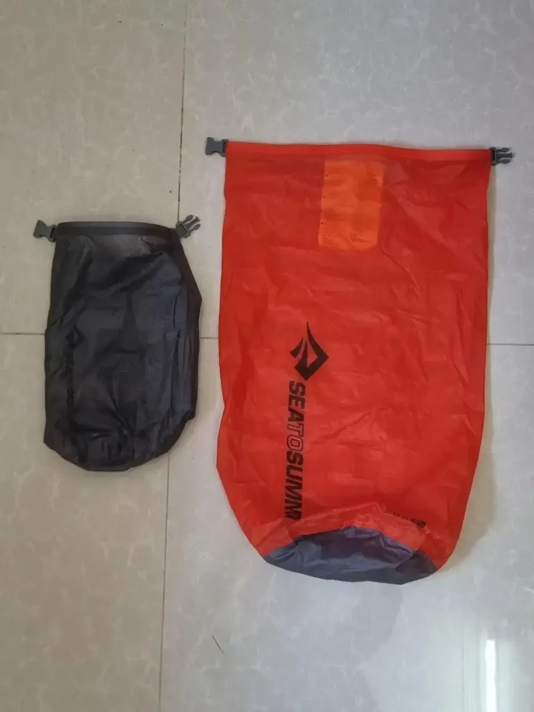 Two stuff sacks, a small and a large one. They are water-resistant, not waterproof. The large one is large enough to old a large laptop. The sacks will not hold a perfect air-tight seal for a long period of time. There is only 1 opening on each sack, the flap of the sack, which has clips sewn on the left and right-hand sides. The way it is closed is by rolling the opening/flap of the sack, and then clipping the two clips together.