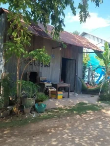 A small shack that someone lives in with a hammock outside. It is along a small dirt path with little traffic that goes by. The shack is made with corrugated steel sheet for the walls and roof. The skeleton frame of the house appears to be wood.
