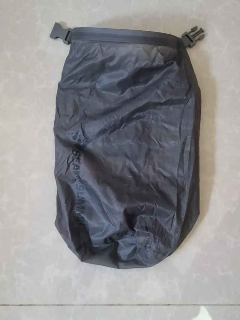 A small stuff sack . It is water-resistant, not waterproof. The sack will not hold a perfect air-tight seal for a long period of time. There is only 1 opening, the flap of the sack, which has clips sewn on the left and right-hand sides. The way it is closed is by rolling the opening/flap of the sack, and then clipping the two clips together.