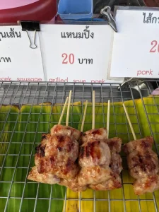 A street food stall in northern Thailand selling grilled sour pork at a price of twenty Thai Baht (about 65 US cents).