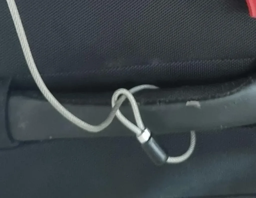 Metal braided travel cable attached to travel bag for tethering it to an anchor object.