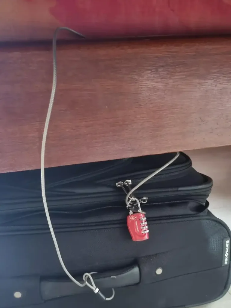 Luggage tethered to an anchor object while traveling using a metal braided travel cable and TSA travel lock.