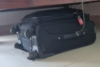 Luggage tethered to an anchor object while traveling using a metal braided travel cable and TSA travel lock.