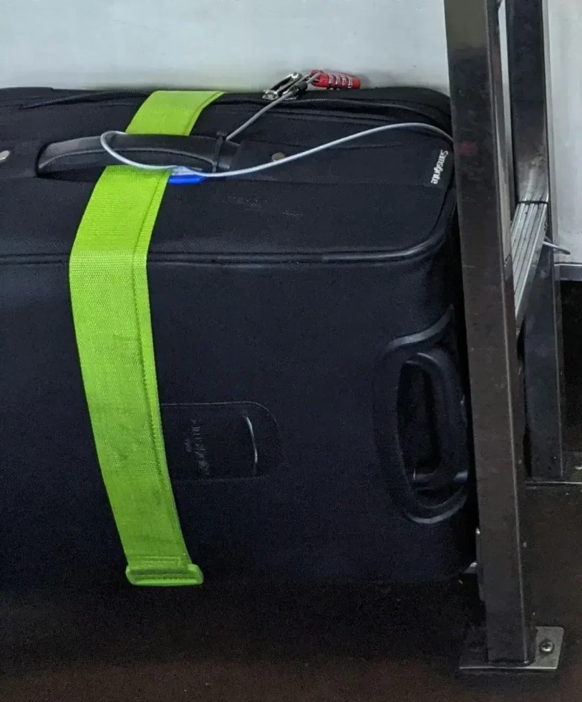 Luggage tethered to an anchor object while traveling using a metal braided travel cable and TSA travel lock.