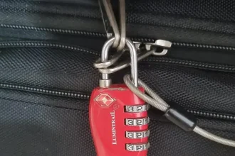TSA travel lock on travel bag. The lock is looped through 2 pairs of zippers. Also, the end loop of a metal travel cable is attached to the lock in order to achor it to an anchor object to prevent theft.