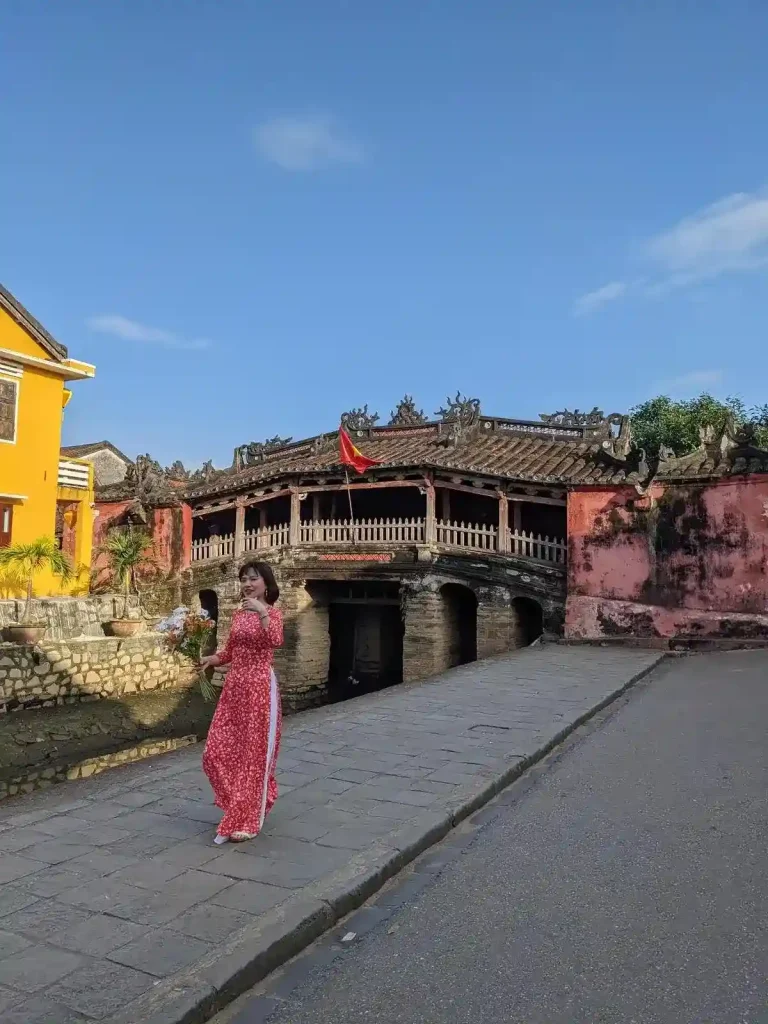 A Vietnamese female wearing an ao dai dress, posing in front of the Japanese bridge in Hoi An, Vietnam.