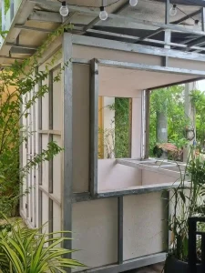 A close-up of a food stall made of welded steel tubing construction in Southeast Asia. The food stall has a stell frame, and has caster wheels on all four corners. It is box shaped at a dimension of approximately six feet wide by six feet long and eight feet tall.