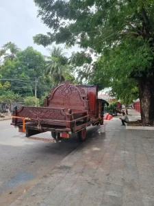 Handmade wooden bed frame with intricate carvings on the back of a trailer. It is for sale along the side of the street in Kampot, Cambodia. This bed frame is solid - certainly not anything cheap!