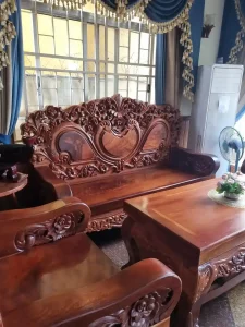 Handmade wooden furniture with intricate carvings in Cambodian home. This furniture is a sofa, chair, and table. This furniture is about four of five inches thick - certainly not anything cheap!