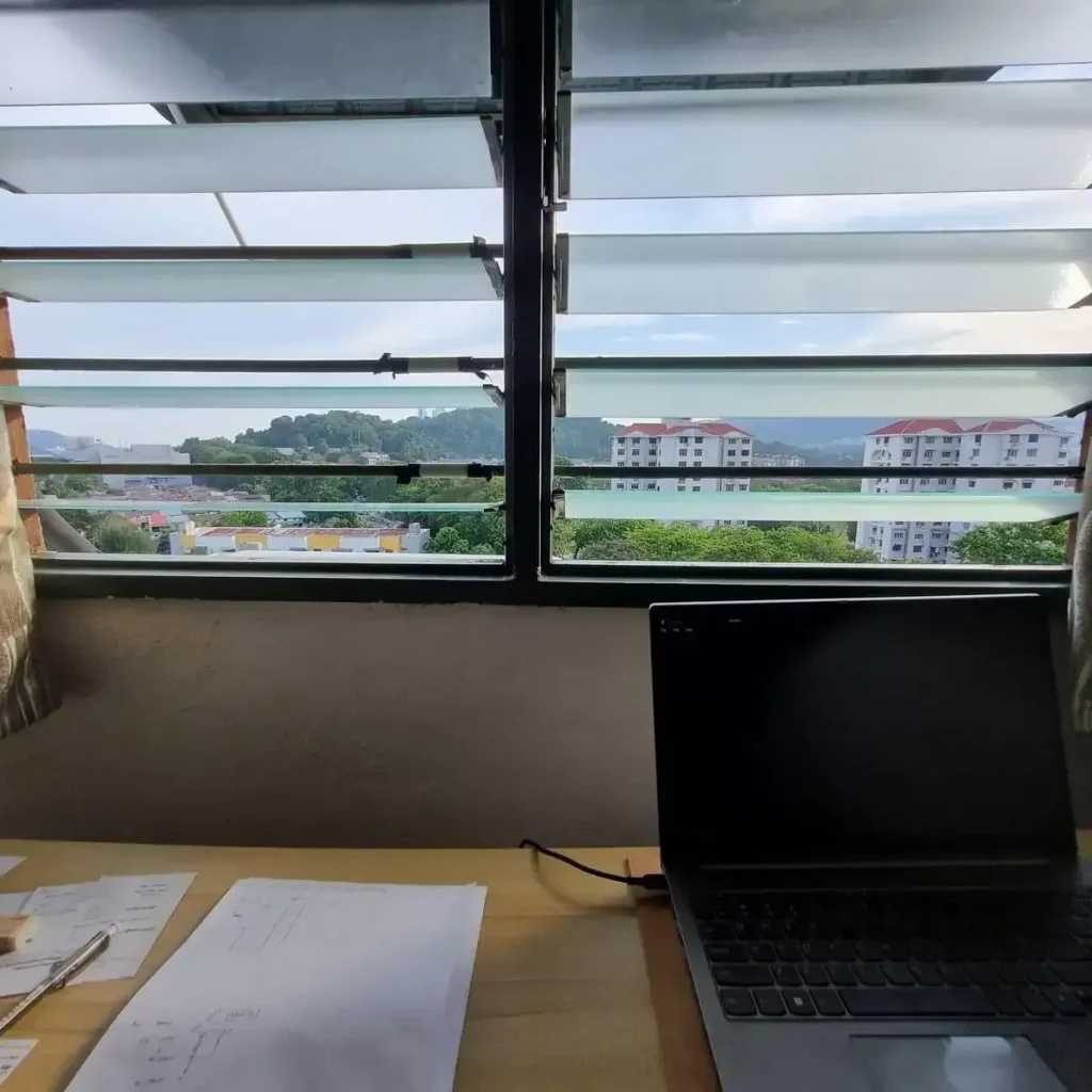 A table with laptop on it looking outside a window in Southeast Asia.