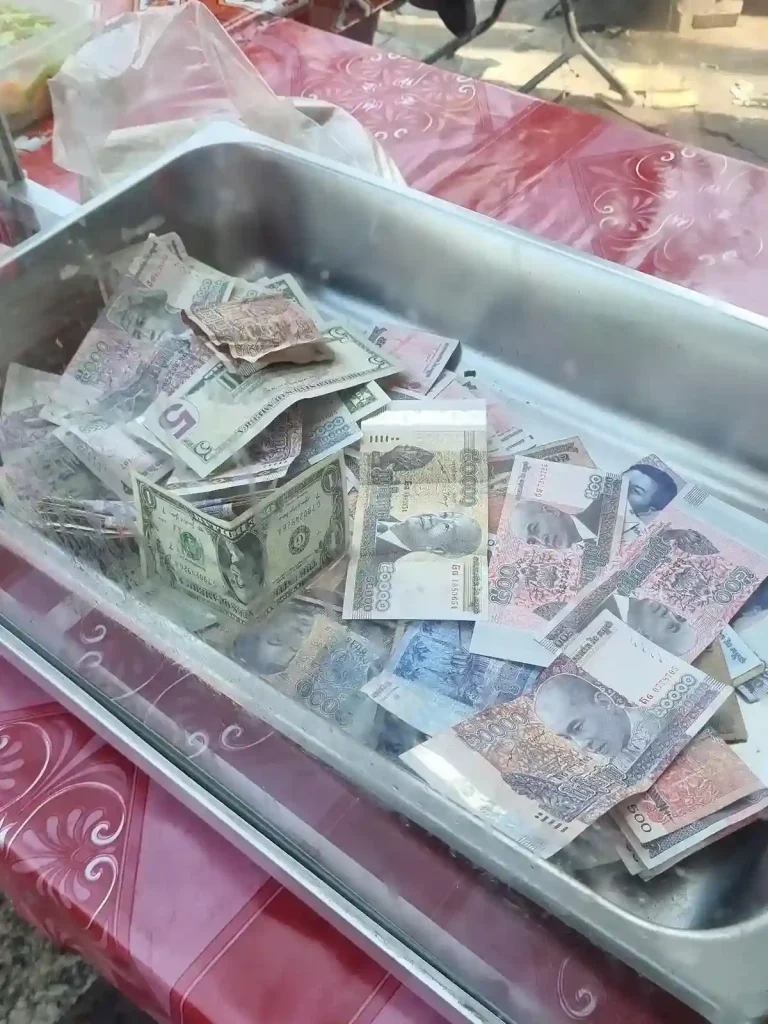 This image of cash thrown into a drawer, unorganized, demonstrates the lack of formal financial accounting in Southeast Asia. This is the cash register at a bahn mi stall in Vietnam.