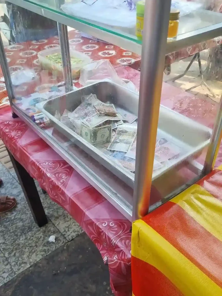 This image of cash thrown into a drawer, unorganized, demonstrates the lack of formal financial accounting in Southeast Asia. This is the cash register at a bahn mi stall in Vietnam.