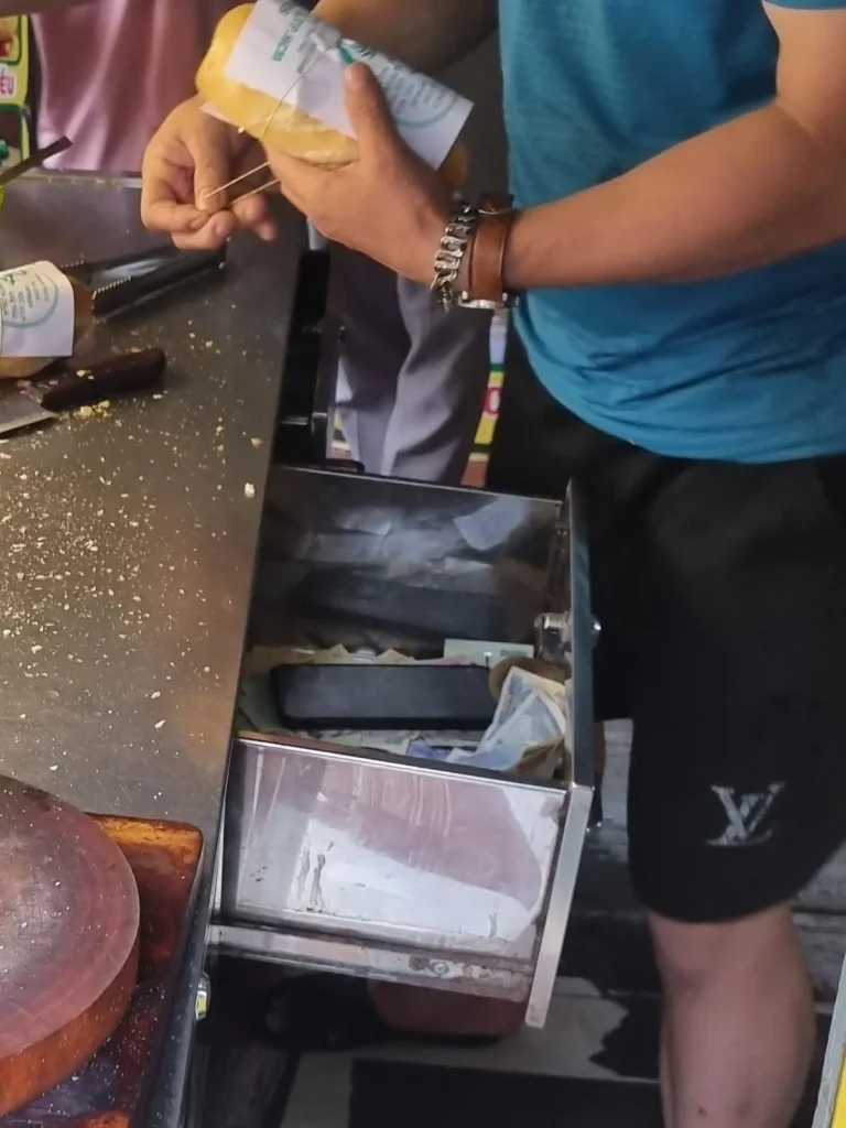 This image of cash thrown into a drawer, unorganized, demonstrates the lack of formal financial accounting in Southeast Asia. This is the cash register at a bahn mi stall in Vietnam.