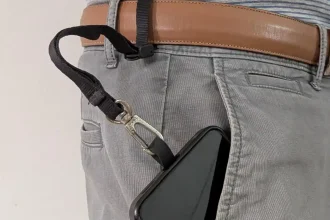 The Blackrapid-brand tether tab and short leash combo tethered & locked onto a pants belt. The belt was fed through the tether, the lock clip was tightened, and then the locked clip was set to the locked position. Since the leash has a quick-attach hook (similar to a rock climbing clip) on the other end, the leash is clipped onto the tether tab mounted on the cellphone. The cellphone is sticking out of the pants pocket to display this leash tether system, but the leash is just long enough for the phone to go completely into the pants pocket. The benefit is to show how the phone cannot be pickpocketed - the leash tether system keeps it securely attached to the hip (the pants belt).
